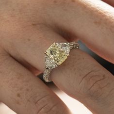 a woman's hand with a yellow and white diamond ring on top of it