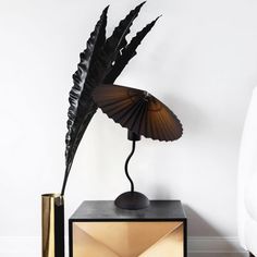 a black and gold lamp sitting on top of a table next to a white wall