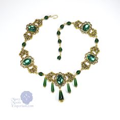 "Noble elegance is conveyed in the richly textured Marquise Xanthe necklace. Smooth glass teardrops capped in filigree dangle sumptuously at the front of this link style necklace while emerald green gems and antique gold swirled links envelop the neck. This necklace closes with a hook clasp and the length is adjustable from 16\" to 20\" to be worn at the length of your choice. Coordinating earrings are also available to complete the set. Also available in black onyx, sapphire blue, ruby red, and Emerald Teardrop Pendant Necklace For Weddings, Ornate Green Jewelry With Jewels, Elegant Jeweled Green Emerald Necklace, May Birthstone Emerald Drop Necklace, Green Emerald Teardrop Pendant Necklace, Emerald Drop Necklace For May Birthstone, Elegant Emerald Jeweled Necklaces, Elegant Jeweled Emerald Necklace, Emerald Jeweled Necklaces As Gifts