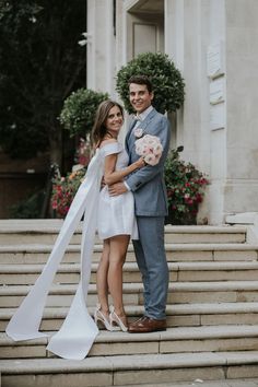 a bride and groom standing on the steps at their wedding