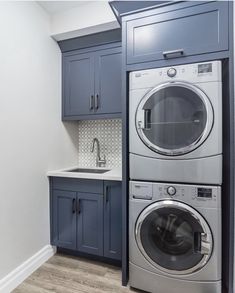 a washer and dryer in a laundry room with blue cabinetry on the walls