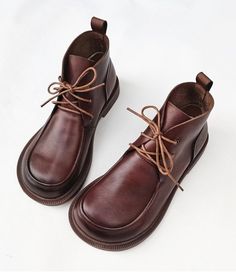 a pair of brown shoes with laces on the top and bottom, sitting on a white surface