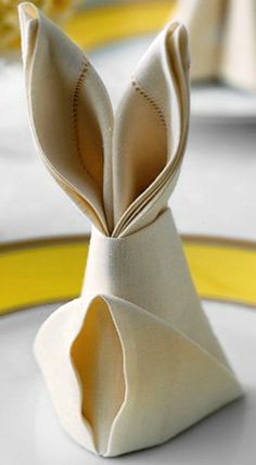 a bunny folded napkin sitting on top of a white plate