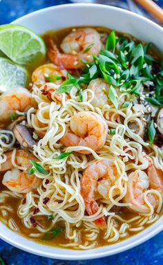 a bowl of shrimp and noodle soup on a blue surface with chopsticks