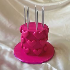 a pink cake with hearts and candles on it