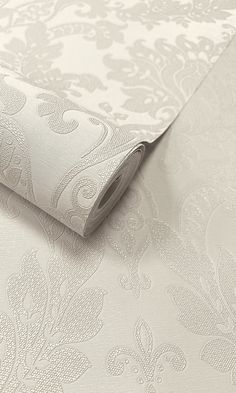 a white wallpaper with an intricate design on it's side and a roll of paper next to it