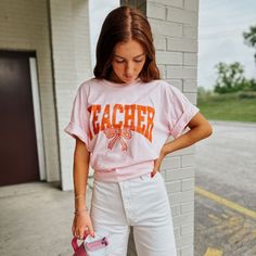 Part of our Teacher's Collection - look at those CUTE little apples in the word 'teacher'! Printed with ink on a Blossom pink 100% cotton Comfort Colors (customer fave!) unisex fitted tee. Adrianna is 5'5 wearing a large. Size up for an oversized fit! Orange Bows, Teacher Tees, Fitted Tee, Workout Tee, Comfort Colors, Apples, Large Size, Blossom, Orange