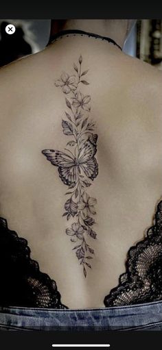 the back of a woman's body with flowers and butterflies on it, behind her is a butterfly tattoo