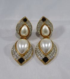 "The past will always return in the fashion world and this piece is back for round two! In the 1920's ladies of class wore the most opulent dresses with jewelry to match. As the years continued, jewelry makers tailored pieces to fashion and trends which resulted in affordability for style. Presenting these Beautiful Vintage Gold Tone Creamy Pearl Cabochon Drop Clip-On Earrings Featuring White Rhinestone Accented Design. Approximate Size: 3.00\" overall length by 1.25\" Wide. Don't forget to LIKE Vintage Jeweled Jewelry For Evening, Formal Jeweled Costume Jewelry Earrings, Formal Costume Jewelry Earrings With Jewels, Vintage Jeweled Clip-on Earrings For Evening, Classic Clip-on Earrings For Vintage Events, Formal Jeweled Drop Clip-on Earrings, Vintage Pearl Drop Jewelry For Formal Occasions, Elegant Clip-on Jewelry For Vintage Events, White Glamorous Clip-on Earrings For Evening