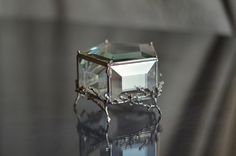 a glass ring sitting on top of a black table next to a silver object with a diamond in it