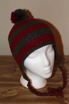 Show off your love of Freddy and A Nightmare On Elm Street with this comfy ear flap hat styled after the killer's signature sweater. Crocheted with matching tassels and a pom pom on top. Fits around a 20-23 inch head circumference. Flap Hat, Ear Flap Hats, A Nightmare On Elm Street, Elm Street, Nightmare On Elm Street, Freddy Krueger, A Nightmare, Head Circumference, Hat Fashion