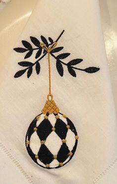 a black and white ornament hanging from a gold thread on a white napkin