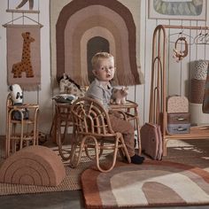 a baby sitting in a toy house with lots of toys on the floor and walls