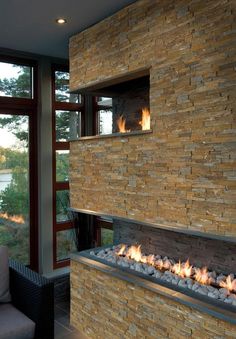 a living room with a fire place next to a large glass window that looks out onto the water