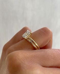 a woman's hand holding a yellow gold ring with a diamond in the middle