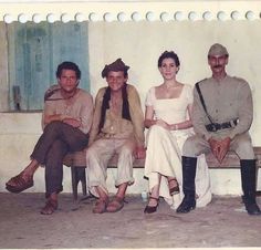 an old photo of four people sitting on a bench