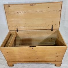 an old wooden chest with no lid on white clothed surface, showing the bottom section