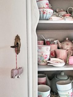 an open cupboard filled with dishes and cups