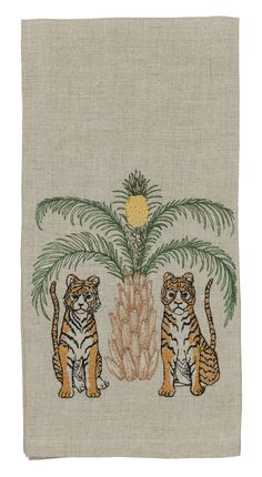 two tigers sitting under a palm tree on top of a white cloth with green leaves