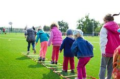 a group of young children standing on top of a green field