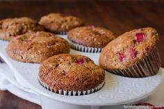 several muffins on a white plate sitting on a wooden table