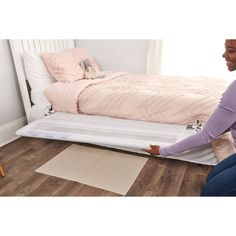 a woman sitting on the floor next to a bed with a pull out bed frame