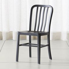 a metal chair sitting on top of a white tile floor next to a curtained window