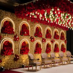 a stage set up with chairs and flowers on the wall for a wedding ceremony or reception