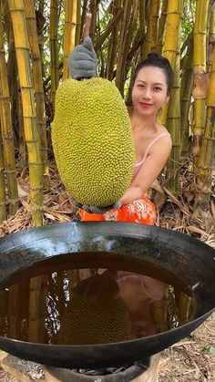 a woman sitting next to a potted plant in front of some bamboo trees and water