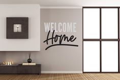 a welcome home wall decal in a living room with wood floors and large windows