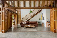 a living room filled with furniture next to a wooden stair case on top of a hard wood floor