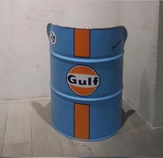 a blue and orange bucket sitting on top of a floor next to a white wall