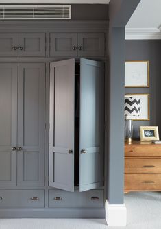 an armoire in the corner of a room with gray walls and drawers on either side