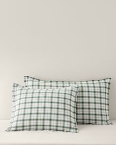 two green and white plaid pillow cases on top of a bed next to each other