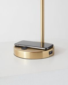 a cell phone is sitting on top of a gold charging station with a black one