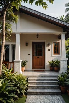 a house with steps leading to the front door and potted plants on either side