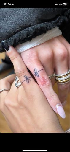 two people with matching rings on their fingers, one is holding the other's finger