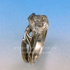 a silver ring with an intricate design on it's side, against a blue background