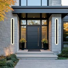 the front entrance to a modern home with two planters on each side and an entry door