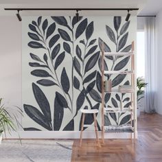 a wall mural with black and white leaves on it in a living room next to a ladder