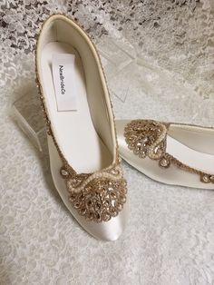 a pair of white shoes with gold embellishments