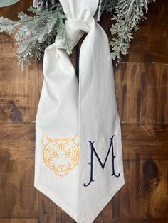 the monogrammed neck tie is tied to a wooden wall with evergreen branches and pine cones