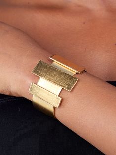 Prepare for endless compliments with this eye-catching bracelet. The Cala Bar Statement Cuff is a striking art-deco-inspired piece featuring a brushed matte 24k gold-plated finish over recycled brass. Its sleek rectangular columns and craftsmanship make it the perfect accessory to elevate your look. Dimensions: Center Accent: 0.59in x 1.77in (15mm x 45mm) Side Accents: 0.39in x 1.37in (10mm x 35mm) Maximum height: 1.7in (45mm) Essence Collection, Wide Cuff Bracelets, Vacation Looks, Bold Art, Wide Cuff, Art Deco Inspired, Wallet Bag, Pop Up Shop, Summer Looks