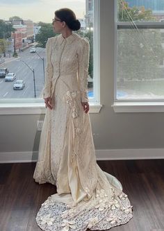 a woman standing in front of a window wearing a dress with flowers on the skirt