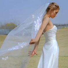 a woman in a white wedding dress holding a veil