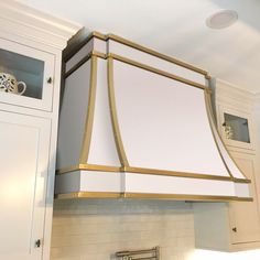 a kitchen with white cabinets and gold trim