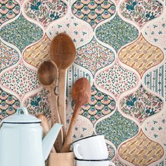 wooden utensils and spoons are lined up against a colorful wallpaper