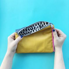 two hands holding a yellow purse with black and white spots