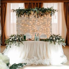 the table is set up with white flowers and greenery for an elegant wedding reception