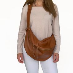 "A favourite and classic leather fanny pack for both women and men that tends to become a timeless design. This large sling bag stands out for the quality of its leather, for the capacity and for the stylish buckle used on the leather strap. It is a 3 style purse as you can wear it as a crossbody bag, as a shoulder bag and as a backpack. The large compartment is ideal to fit all your daily essentials like a water bottle, a make up case, wallet , phone, notebook and more. Ideal for travelling, for vacations and for everyday walks , you will use this bag for many years as it will never go out of style. Crafted from the finest Italian grain leather and matched with quality metal hardware and zippers. The inside of the bag is fully lined with water - repellent fabric in coral color and it has Everyday Soft Leather Pouch Chest Bag, Everyday Smooth Grain Crossbody Belt Bag, Soft Leather Chest Bag For On-the-go, Sling Purse, Fanny Pack Women, Leather Sling Bag, Purse Gift, Leather Fanny Pack, Bag Stand